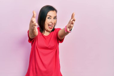 Orta yaşlı İspanyol kadın sıradan kıyafetler giyip kameraya bakıyor. Sarılmak için kollarını açmış gülümsüyor. Mutluluğu kucaklayan neşeli bir ifade.. 