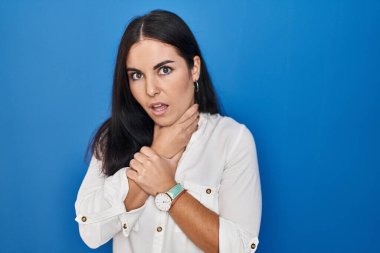 Mavi arka planda dikilen genç İspanyol kadın boğularak öldü diye bağırıyor. Sağlık problemi. Boğulma ve intihar konsepti. 