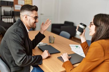 İki İspanyol iş adamı gülümseyerek ofiste kahve içiyorlar..