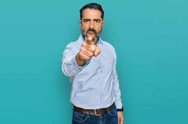 Sakallı, iş gömleği giyen orta yaşlı bir adam kameraya kızgın ve sinirli olduğunu gösteriyor. 