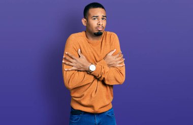 Genç, Afro-Amerikan bir adam günlük giysiler giyiyor. Kış soğuğu için titriyor ve donuyor. Yüzünde üzgün ve şok ifadesi var. 