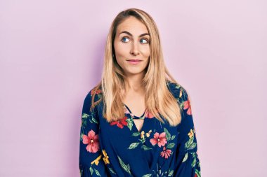 Gündelik giysiler giymiş genç beyaz kadın gülümseyip yan tarafa bakıyor ve düşünüyor.. 