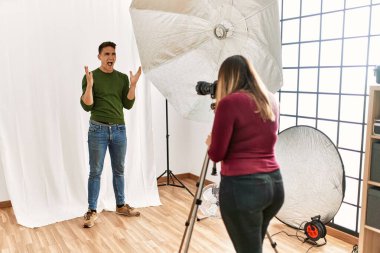 Young man at photography studio crazy and mad shouting and yelling with aggressive expression and arms raised. frustration concept. 