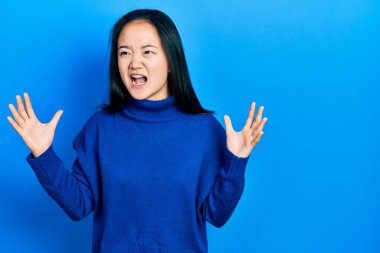 Sıradan kıyafetler giyen genç Çinli bir kız. Deli gibi bağırıyor, agresif bir ifadeyle bağırıyor ve kollarını kaldırıyor. hüsran kavramı. 