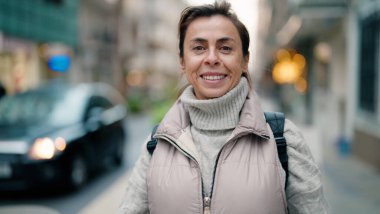 Orta yaşlı İspanyol kadın sokakta kendine güvenerek gülümsüyor.