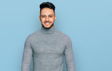 Yüzünde mutlu ve havalı bir gülümseme olan sıradan kıyafetler giyen genç bir Arap. şanslı kişi. 