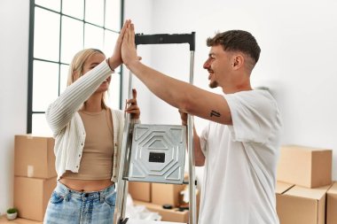 Kafkasyalı genç çift yeni evinde işçi merdivenlerini tutarken beşlik çakıyor..