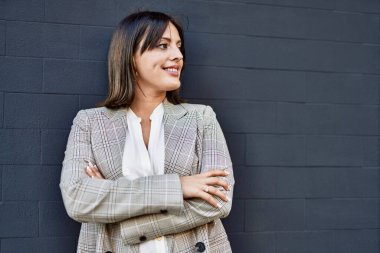 Genç İspanyol iş kadını şehirde çapraz hareketlerle mutlu gülümsüyor..