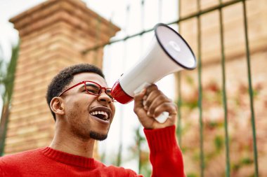Yakışıklı Afrikalı Amerikalı genç adam megafonla bağırıyor.