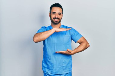 Sakallı, mavi erkek hemşire üniforması giyen, iri ve büyük boy işaretler gösteren yakışıklı İspanyol bir adam. Kameraya bakıp gülümsüyor. ölçüm kavramı. 