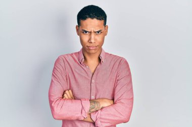 Genç, Afro-Amerikalı, sıradan kıyafetler giyen, kuşkucu ve gergin, yüzünde çapraz kollu tasvip etmeyen bir ifade var. negatif kişi. 