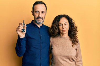 Orta yaşlı İspanyol çift ellerinde yeni evlerinin anahtarlarını tutarken düşünceli tavırları ve ayık ifadeleri kendilerine güveniyorlar. 