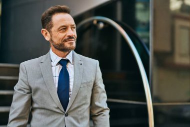 Orta yaşlı işadamı şehirde mutlu mesut dikilirken.