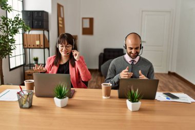 Ofiste laptopla görüntülü arama yaptığı için mutlu gülümseyen iki çağrı merkezi ajanı..