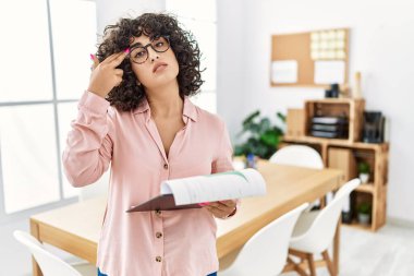 Ortadoğulu genç bir kadın, iş yerinde iş elbisesi giyip, silah gibi el ve parmakları işaret ederek kendini vuruyor, intihar jesti.. 