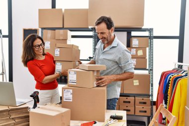 Orta yaşlı erkek ve kadın iş ortakları depoda paket tutarken güler yüzlü.