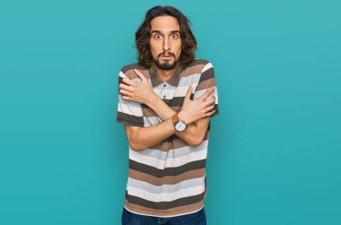 Latin kökenli genç bir adam günlük kıyafetler giyiyor. Kış soğuğu için titriyor ve donuyor. Yüzünde üzgün ve şok ifadesi var. 