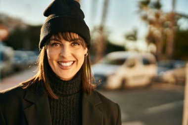 Genç İspanyol kadın gülümseyerek şehirde mutlu mesut dikiliyor..