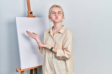 Sarışın, güzel beyaz kadın boyacı tezgahının yanında durup komik suratlı kanva şişen yanaklarını sunuyor. Ağzı havayla şişer, havayı yakalar.. 