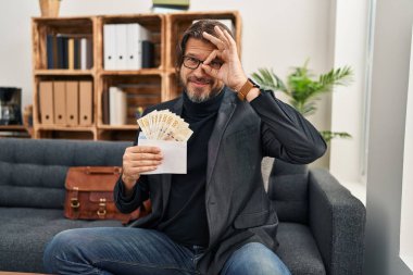 Muayenehanedeki yakışıklı orta yaşlı adam elinde DKK banknotları tutarken mutlu mesut gülümsüyor. 