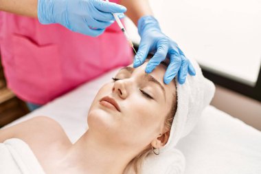 Klinikteki yaşlanma karşıtı tedavi için kadın yüzüne botoks yapan doktor..