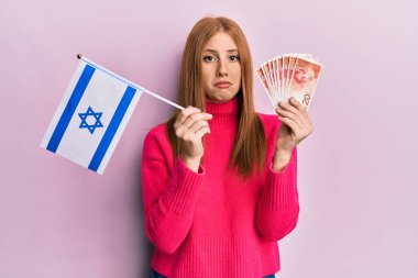 Genç İrlandalı kadın İsrail bayrağını tutuyor ve şekeller para basıyor. Depresyonda ve endişe içinde, kızgın ve korkmuş bir şekilde ağlıyor. hüzünlü ifade. 