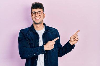 Gündelik kıyafetler giyen, gözlüklü, gülümseyen ve kameraya bakan genç İspanyol bir adam.. 