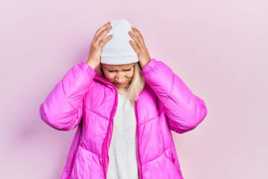 Kafkasyalı güzel sarışın kadın yün şapka ve kışlık ceket giyiyor. Ağrı ve migren yüzünden baş ağrısı çekiyor ve strese giriyor. Eller başının üstünde.. 