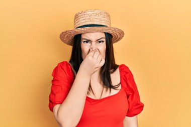 Yaz şapkası takan genç İspanyol kadın pis ve iğrenç bir koku alıyor. Nefesini burnunda tutuyor. Kötü kokuyor. 