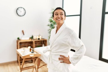 Bornoz giyen genç İspanyol kadın güzellik merkezine güvenerek gülümsüyor.