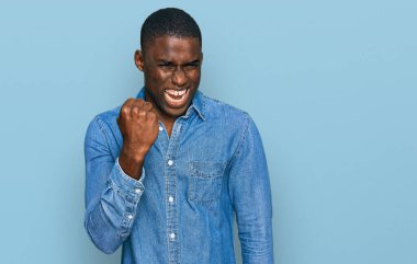 Genç, Afro-Amerikan bir adam, günlük kıyafetler giyiyor kızgın ve kızgın. Öfkeyle bağırırken yumruğunu kaldırıyor. öfke ve agresif konsept. 