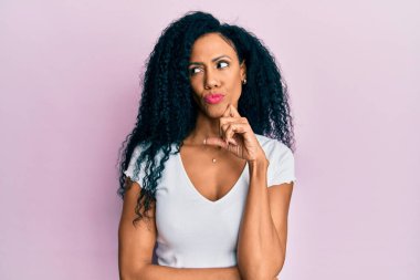 Orta yaşlı Afro-Amerikalı kadın günlük beyaz t-shirt giyiyordu. Düşünceleri kuşkuya yoğunlaşmıştı. Parmakları çenesinde ve yukarı bakıyordu. 