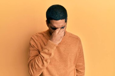 Sıradan bir kazak giyen genç, yakışıklı İspanyol adam yorgun burnu ve gözleri ovuşturup yorgun ve baş ağrısı çekiyor. Stres ve hüsran kavramı. 