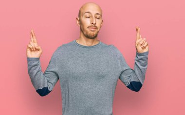 Kel, sakallı, sıradan kıyafetler giyen, el işareti yapan, umut dolu ve gözleri kapalı bir şekilde gülümseyen bir adam. Şans ve batıl inançlar. 