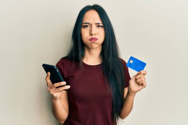 Akıllı telefon ve kredi kartı şişiren komik yüzlü genç İspanyol kız. Ağzı havayla şişer, havayı yakalar.. 