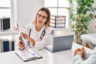 Genç adam ve kadın doktor ve hasta klinikte tıbbi danışmanlık yapıyorlar.