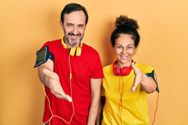 Orta yaşlı bir çift İspanyol kadın ve erkek spor giyer ve kol bandı takar dostça el sıkışarak selamlaşırlar. başarılı iş. 