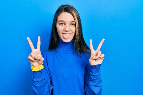 터틀넥 스웨터를 소녀는 손가락으로 승리의 표시를 웃으며 — 스톡 사진