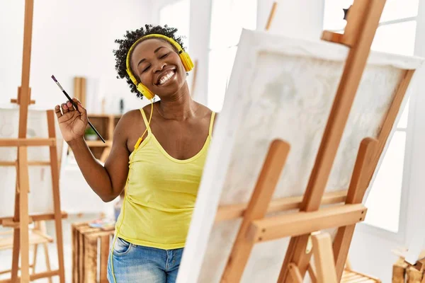 在艺术工作室用耳机画画的年轻非洲裔美国女艺术家 — 图库照片