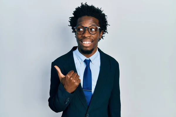若いアフリカ系アメリカ人の男を身に着けているビジネススーツ笑顔で幸せな顔を見てと親指で側面を指してアップ — ストック写真