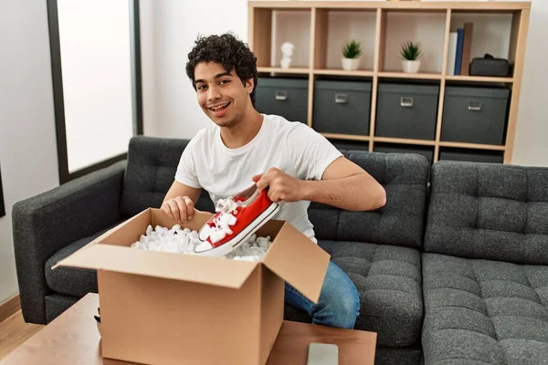 Young Hispanic Man Unboxing Sneakers Cardboard Box Sitting Sofa Home — Stock Photo, Image