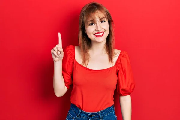 Kırmızı Tişörtlü Kızıl Saçlı Genç Bir Kadın Bir Numarayı Gösterip — Stok fotoğraf