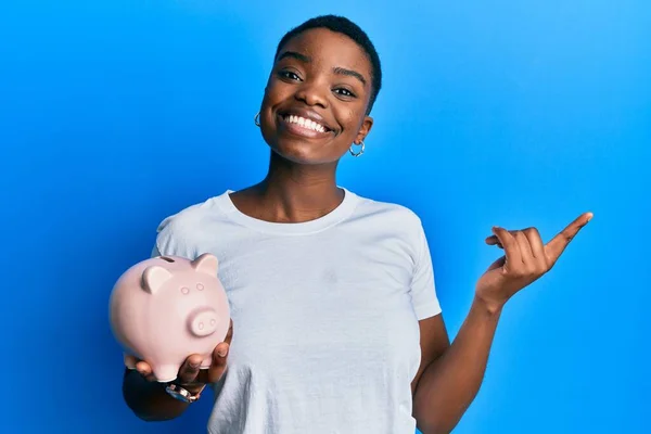 Mladá Africká Americká Žena Drží Prasátko Banka Úsměvem Šťastný Ukazující — Stock fotografie