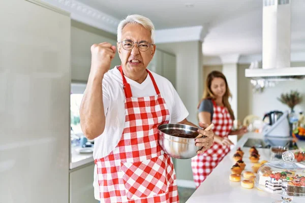 Middle Age Hispanic Couple Wearing Apron Cooking Homemade Pastry Annoyed — Stock Photo, Image