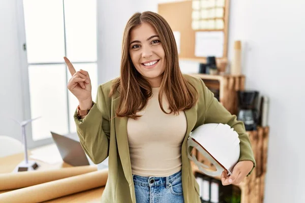 Joven Morena Sosteniendo Arquitecto Hardhat Oficina Sonriendo Feliz Señalando Con —  Fotos de Stock