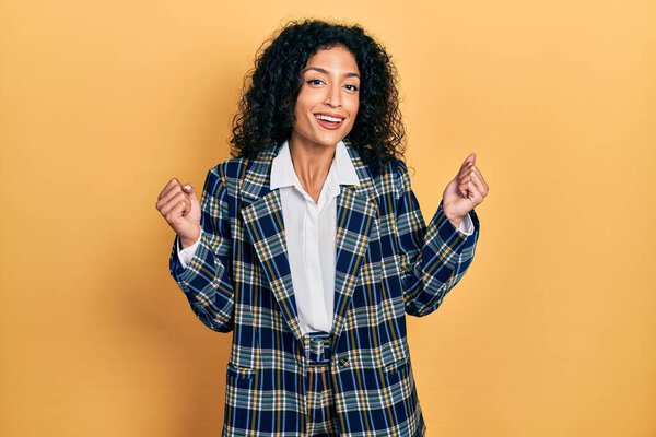 Молодая латиноамериканка в деловой одежде радовалась и удивлялась успеху с поднятыми руками и открытыми глазами. победитель концепция. 