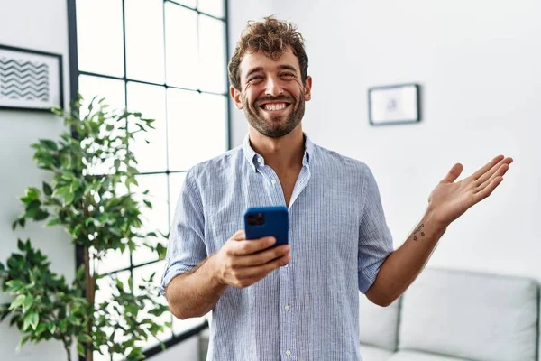 Genç Yakışıklı Adam Evde Akıllı Telefon Kullanarak Başarıyı Mutlu Bir — Stok fotoğraf