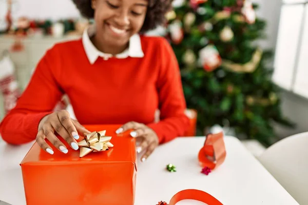 Joven Mujer Afroamericana Sonriendo Confiado Embalaje Regalo Navidad Casa —  Fotos de Stock