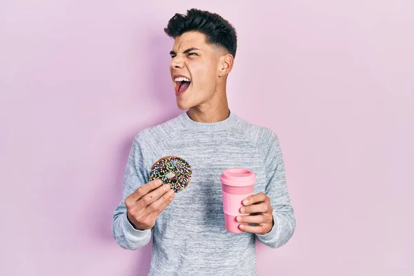 Молодой Латиноамериканец Ест Пончики Пьет Кофе Злой Безумный Кричащий Расстроенный — стоковое фото