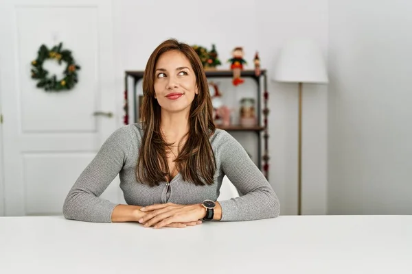 Mujer Latina Joven Sentada Mesa Por Decoración Navidad Sonriendo Mirando —  Fotos de Stock
